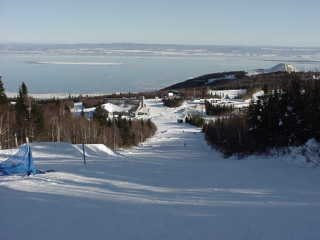 Le Massif's terrain park (foreground), the new summit lodge (middleground), the "mound" atop Cap Maillard (background right) and the St. Lawrence River are all visible in this photo. (photo: Marc Guido)