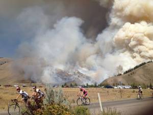 Cyclists in the annual LOTOJA race from Logan, Utah to Jackson, Wyo. on Saturday pass the Little Horsethief Fire that threatens Wyoming's Snow King ski area. (photo: InciWeb)