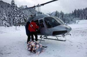 Crystal Mountain patrollers load large bags of explosives into a waiting helicopter last Friday. (photo: Crystal Mountain Resort)