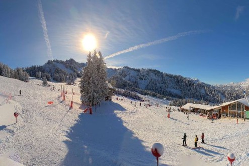 Blue skies and sun shining above skier lined snow-covered ski slopes in Châtel, France – Weather to ski – Today in the Alps, 11 January 2026